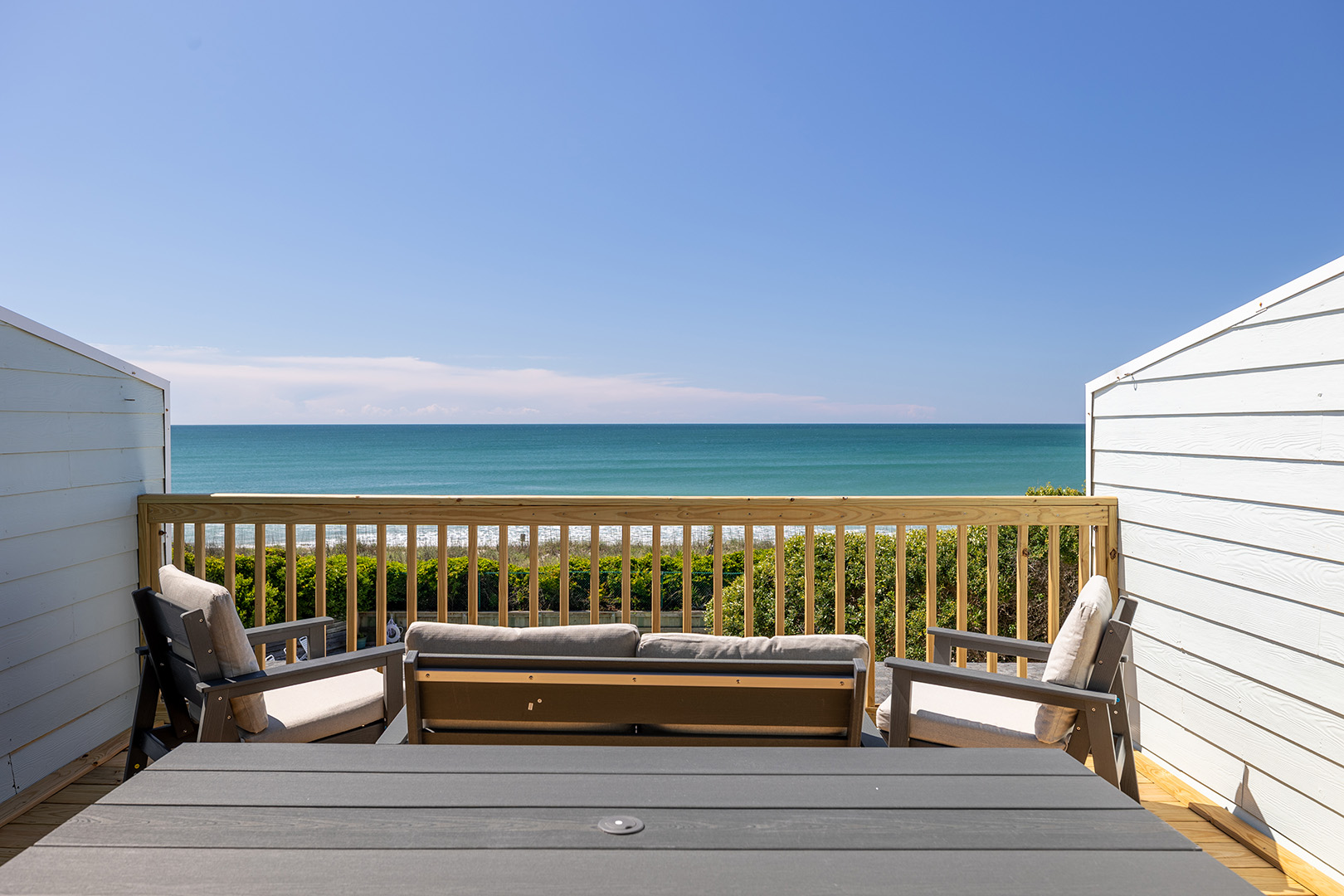 Oceanfront deck with dining table and lounge chairs at Coral Shores 12