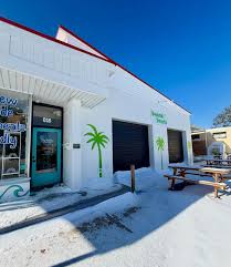 Exterior of Beach Bowls in Beaufort, a white building with turquoise door and palm tree murals